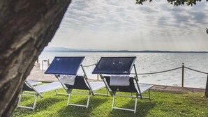 A row of sun loungers with solar panels on a grassy area overlooking a body of water. - Hotel Fonte Boiola (Sirmione)