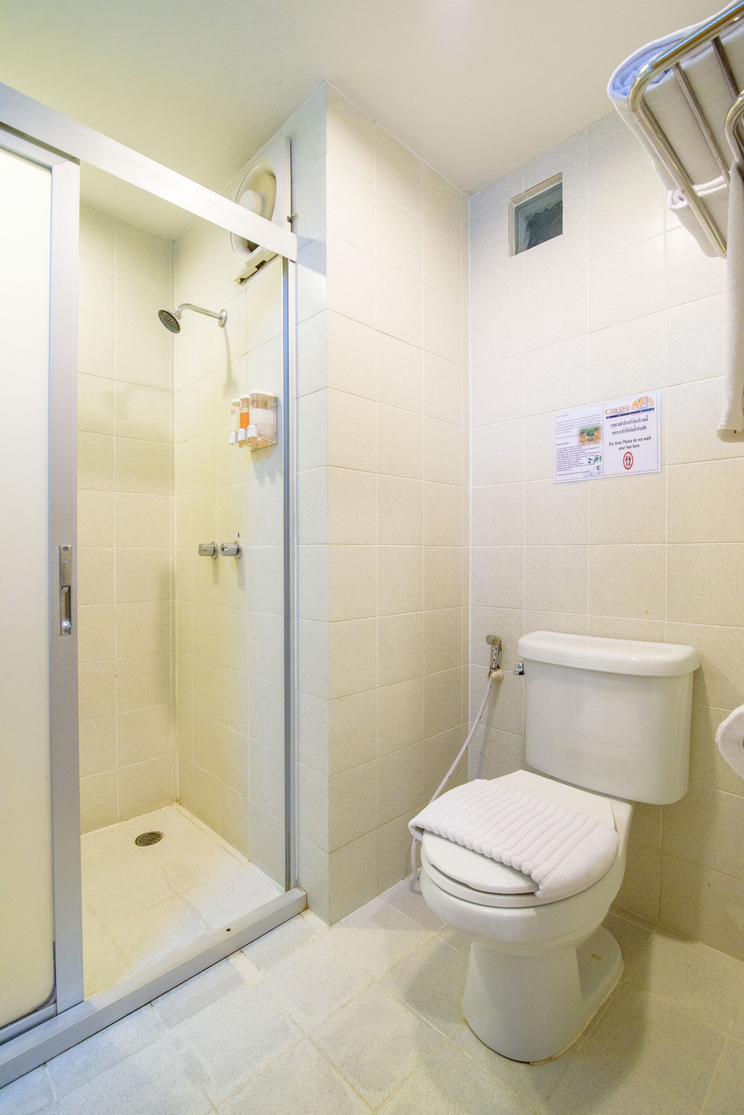 A bathroom with a shower, toilet, and a small window.
