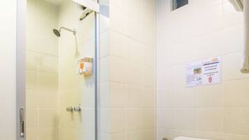A bathroom with a shower, toilet, and a small window.