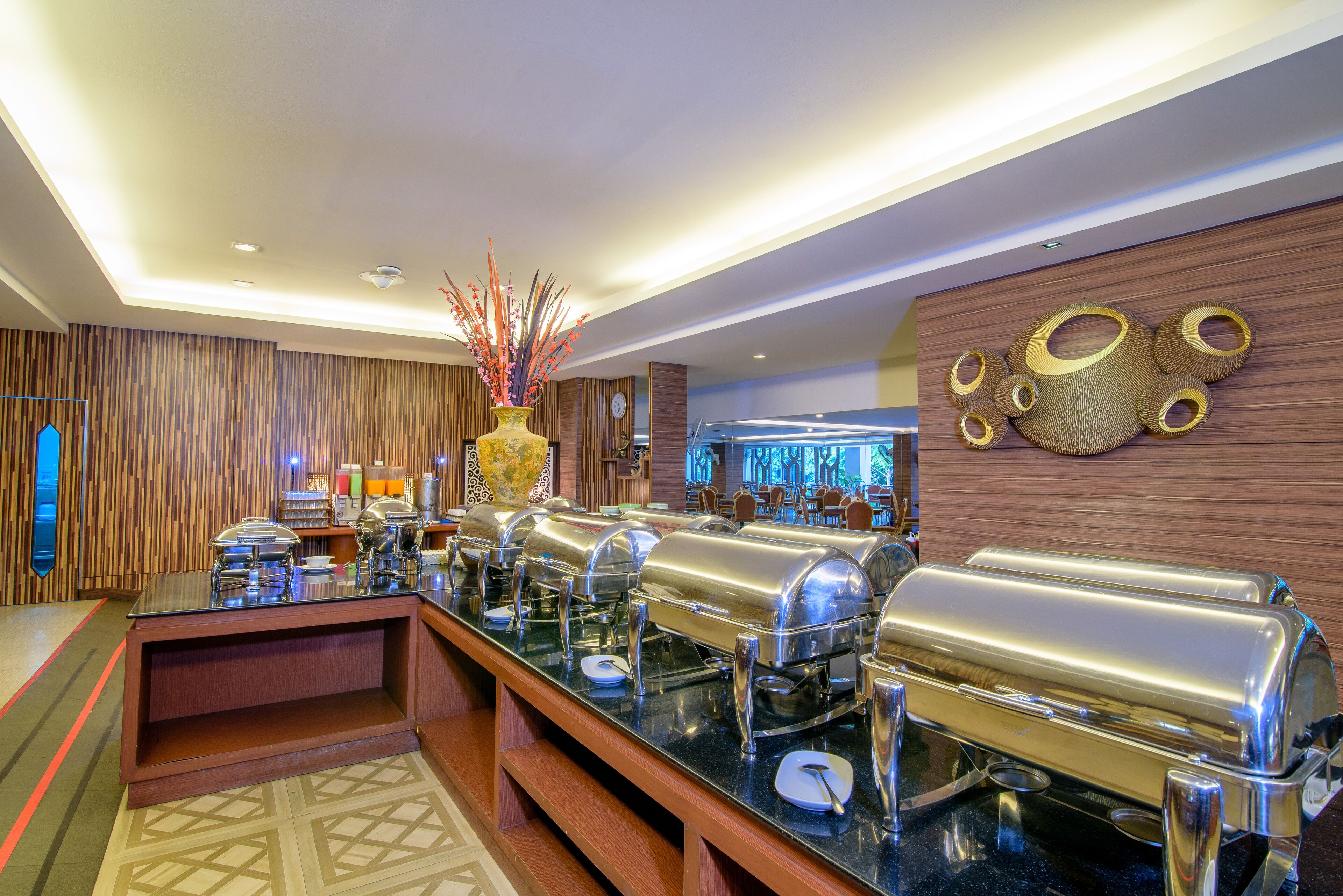 Un'area buffet con diverse postazioni di servizio, un vaso decorativo e una parete con motivi circolari.