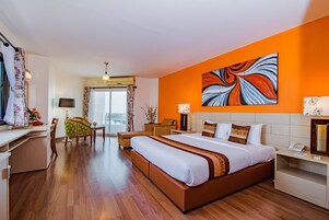 Habitación de hotel con una cama grande, un escritorio, una silla, una mesa de comedor y vistas al exterior.