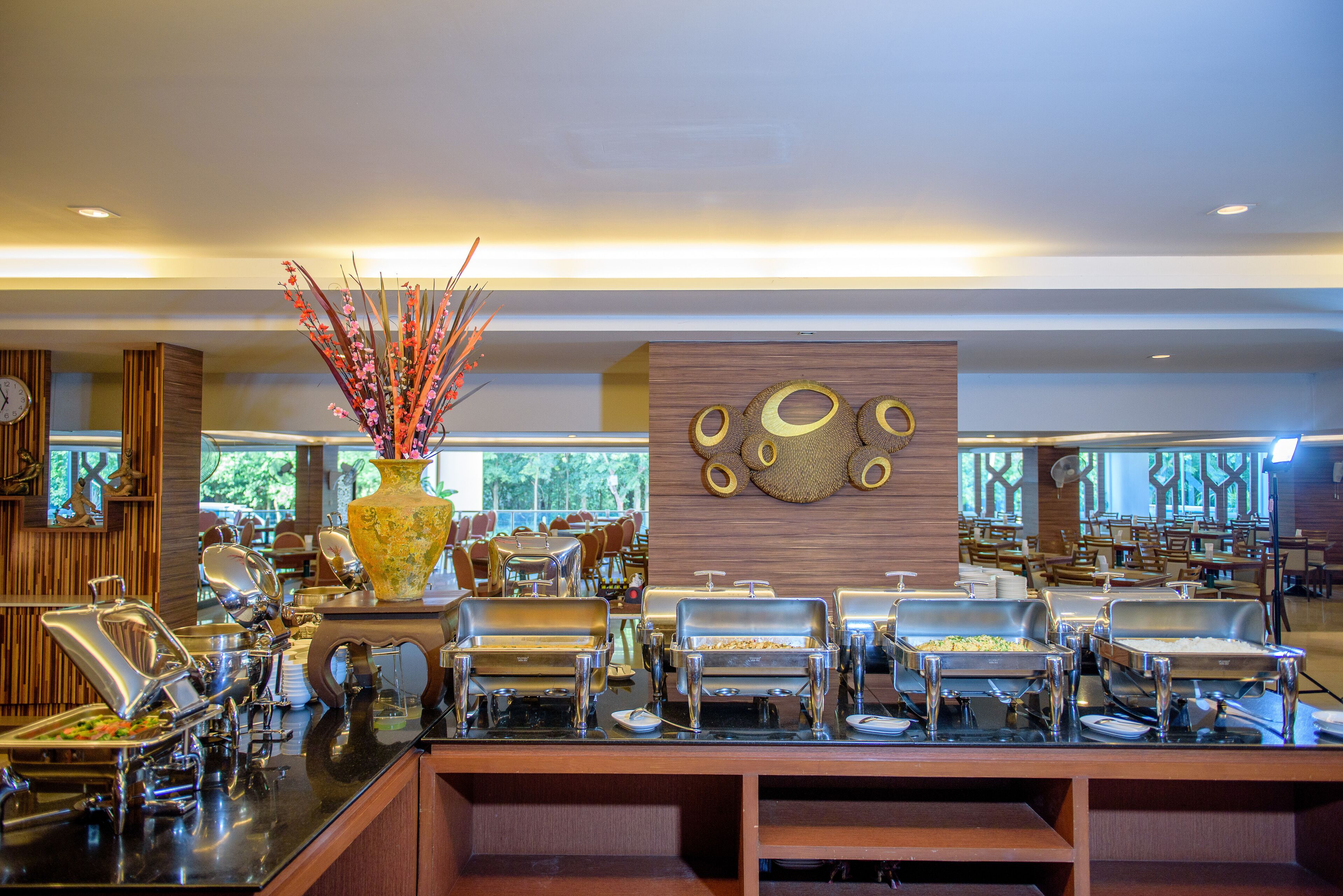A buffet area with multiple serving stations, a decorative vase, and a wall with circular patterns.