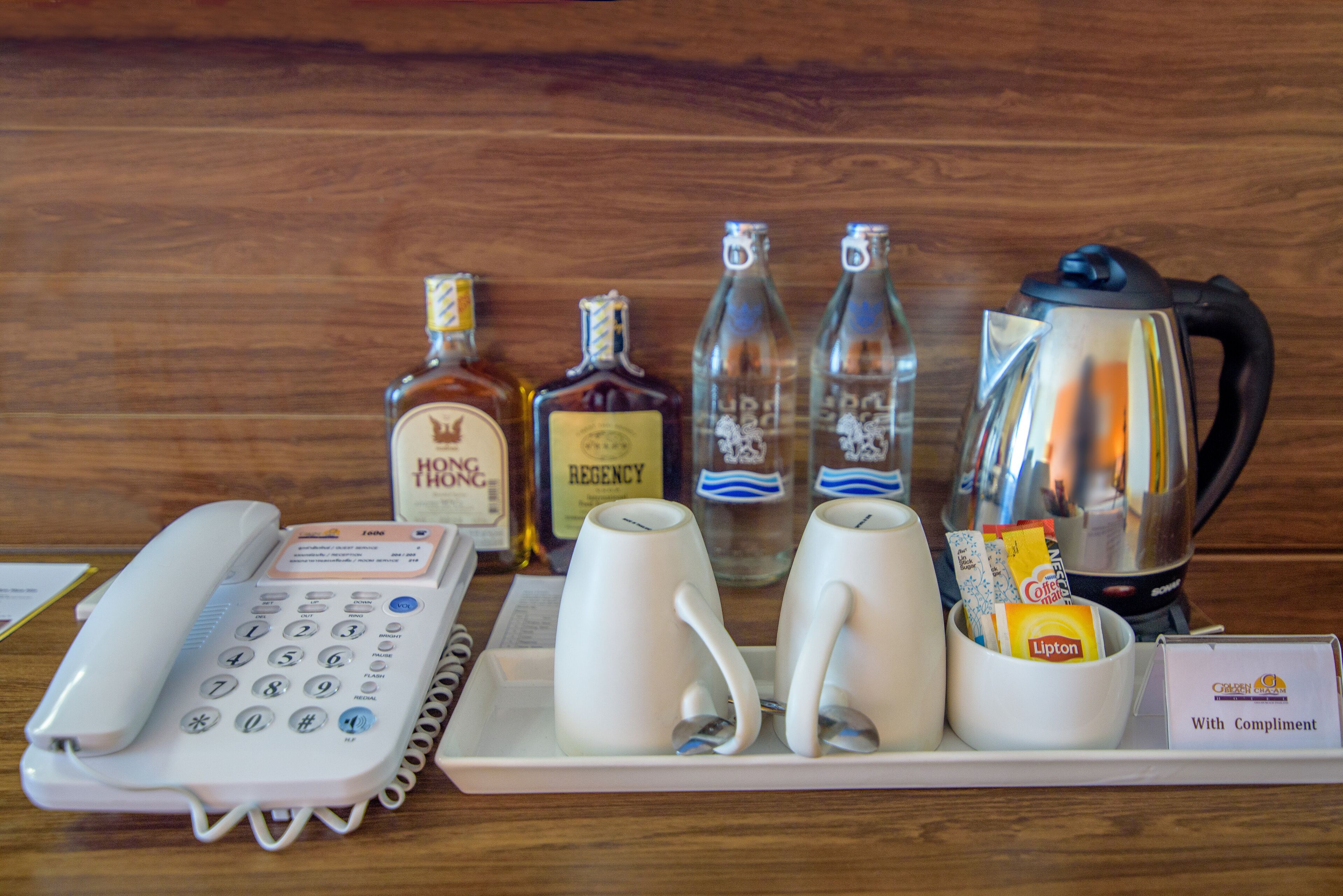 Un comptoir d’accueil d’hôtel avec un téléphone, deux tasses, une cafetière et un plateau contenant des sachets de thé Lipton.