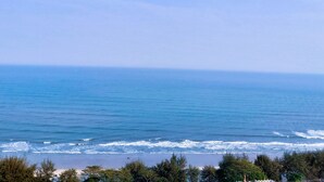 A beach with waves and trees in the foreground. - Golden Beach Cha-Am Hotel (Cha-am)