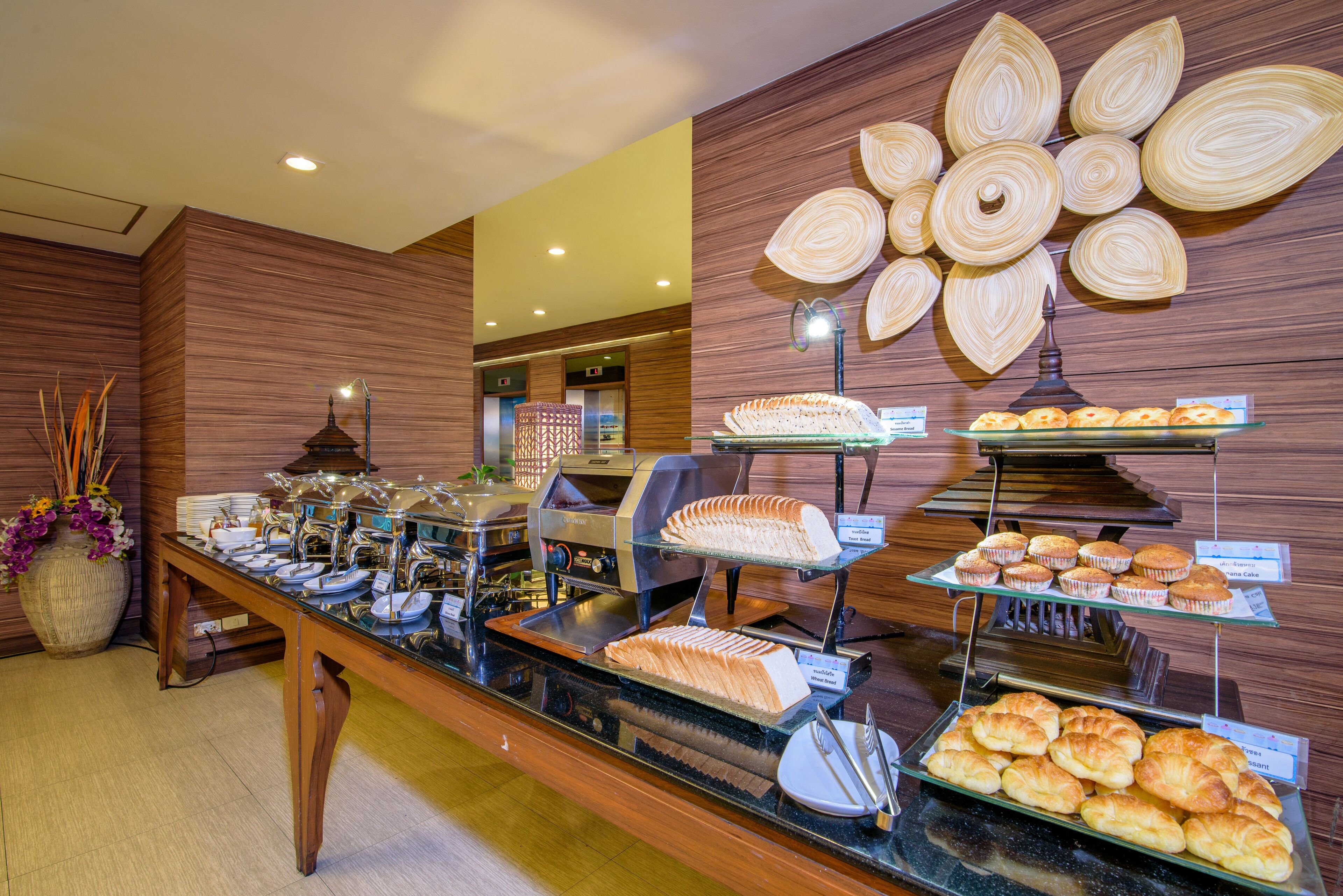 A buffet with various food items, including pastries and sandwiches, displayed on glass shelves.