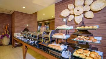 A buffet with various food items, including pastries and sandwiches, displayed on glass shelves.
