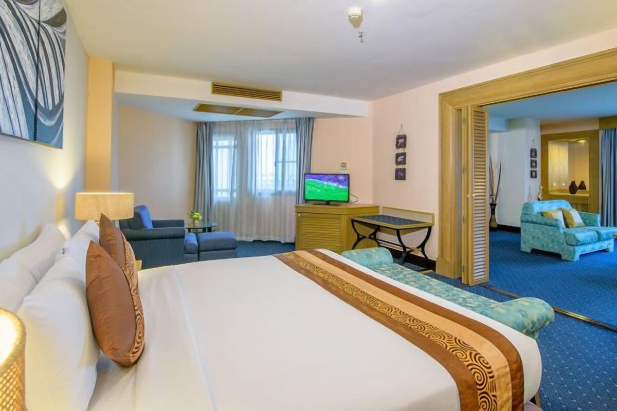 Habitación de hotel con cama, televisor, escritorio y zona de estar.