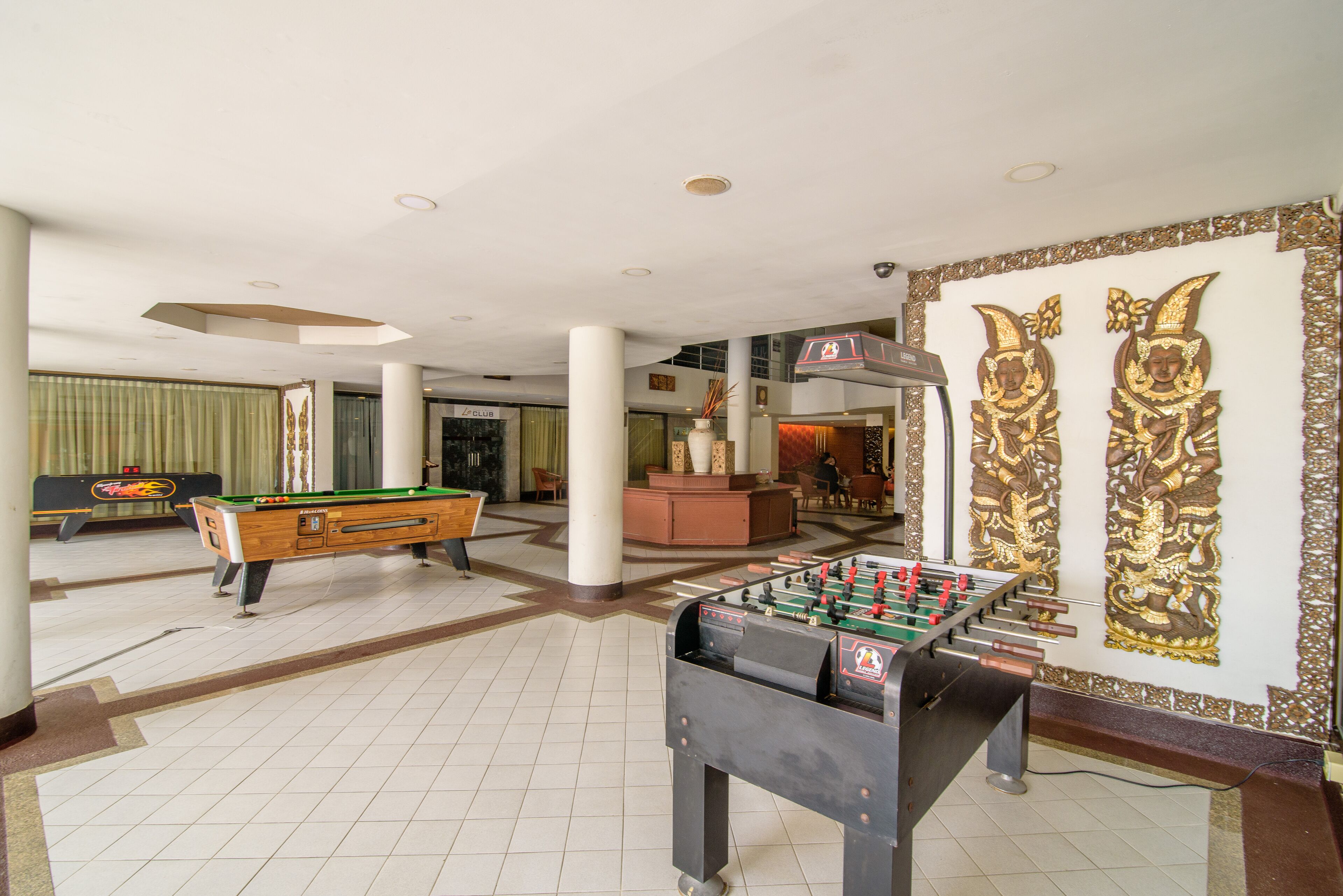 A spacious lobby with a pool table, a foosball table, and a bar area.