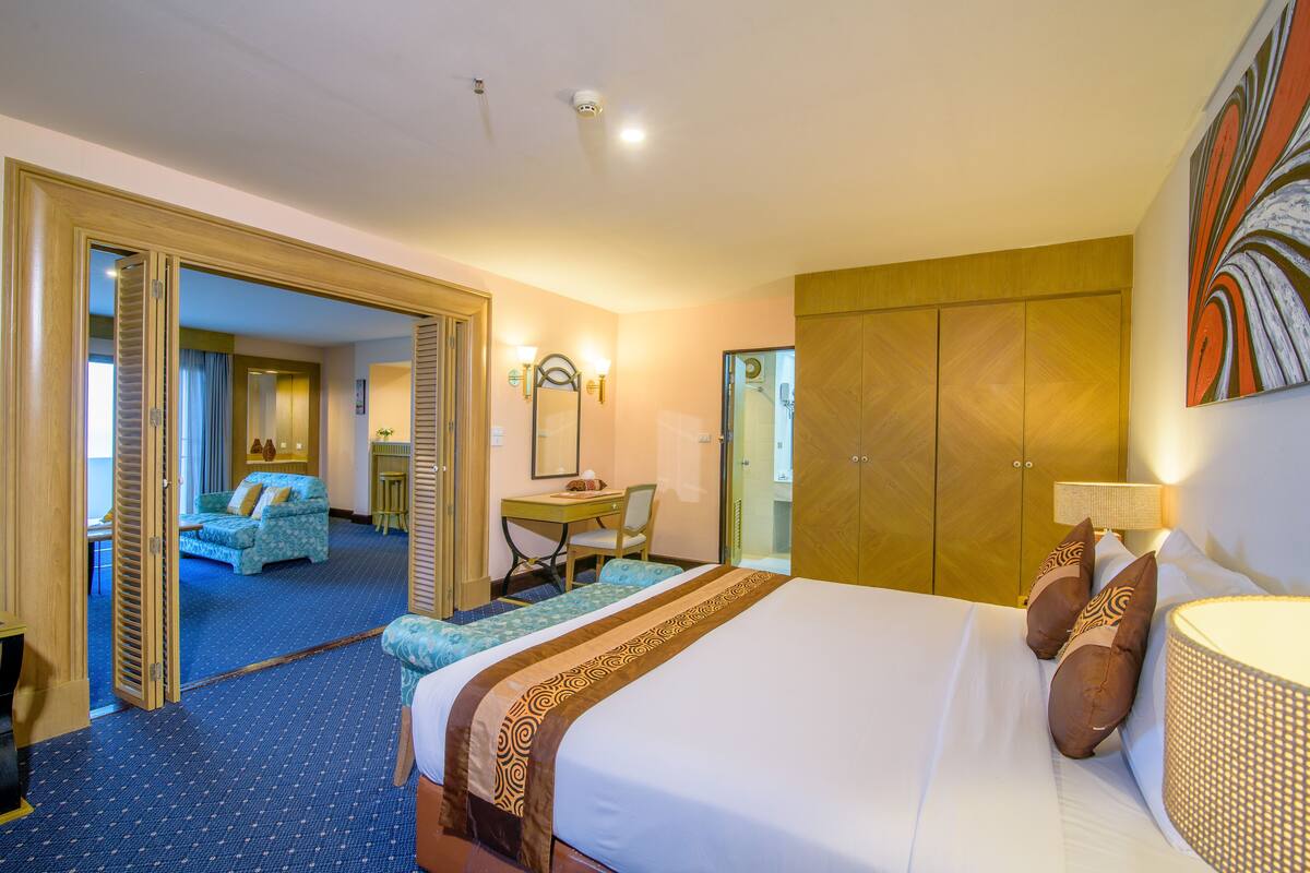Hotelkamer met een groot bed, een bureau, een stoel, een kledingkast en een zichtbare badkamer door een geopende deur.