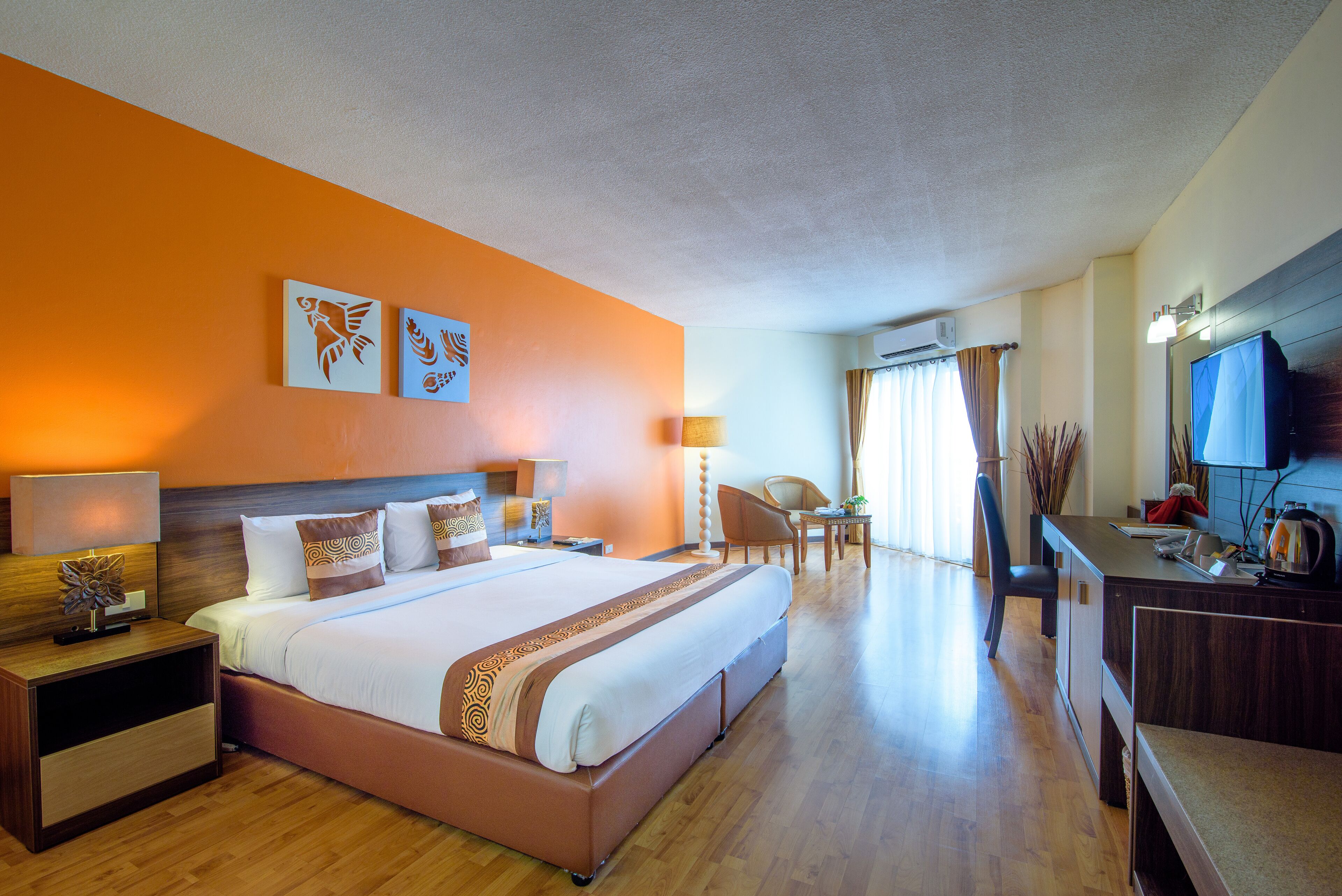 A hotel room with a large bed, a desk, a chair, and a television.