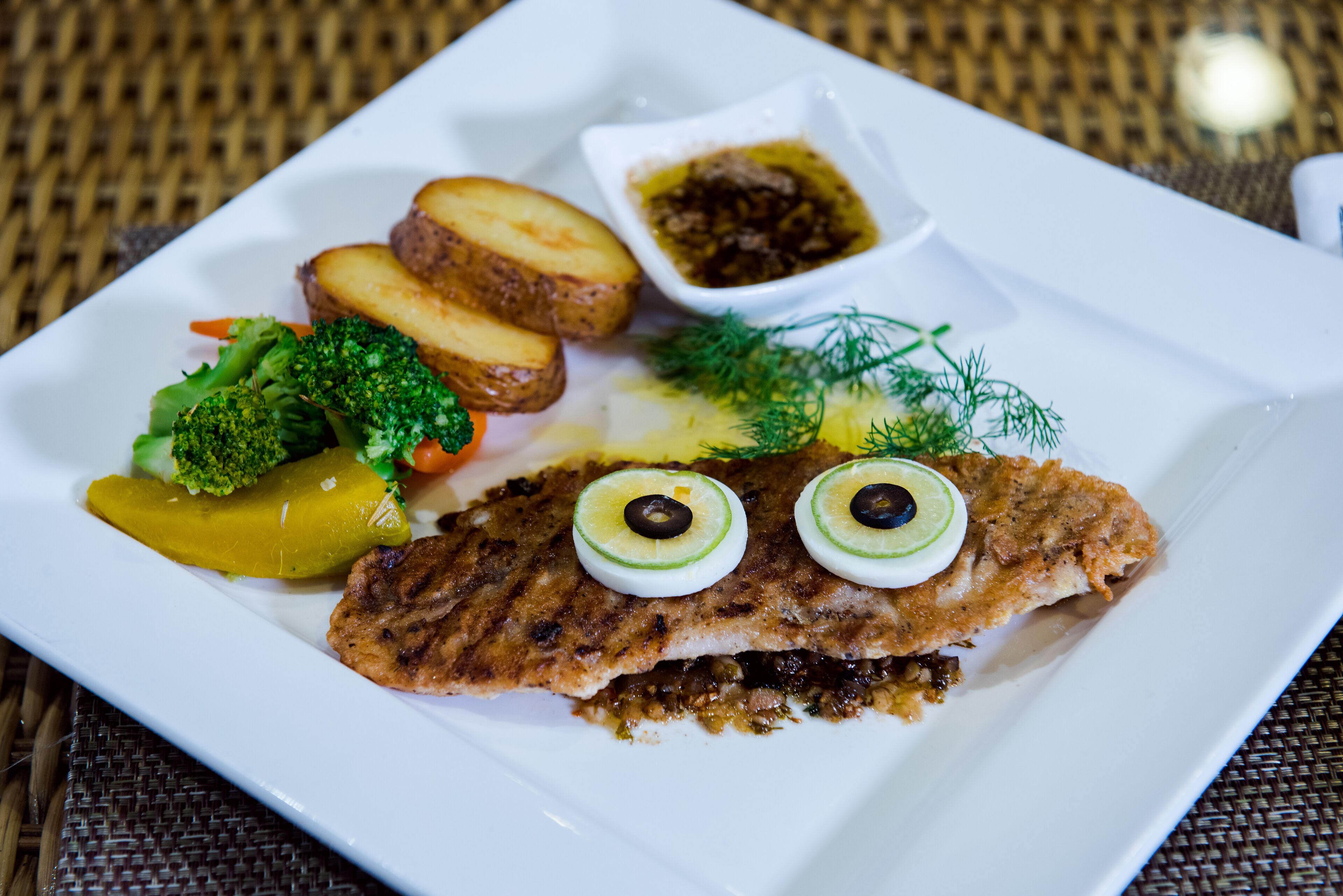 A plate of food with a fish fillet, bread, and vegetables.