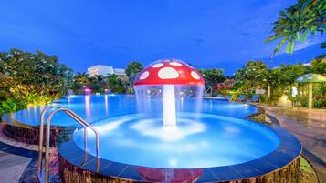 Relax by the unique water feature, surrounded by lush tropical plants and palm trees.
