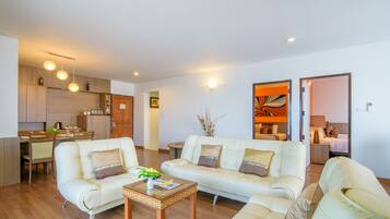 A modern living room with a sofa, a coffee table, and a dining area with chairs and a table.