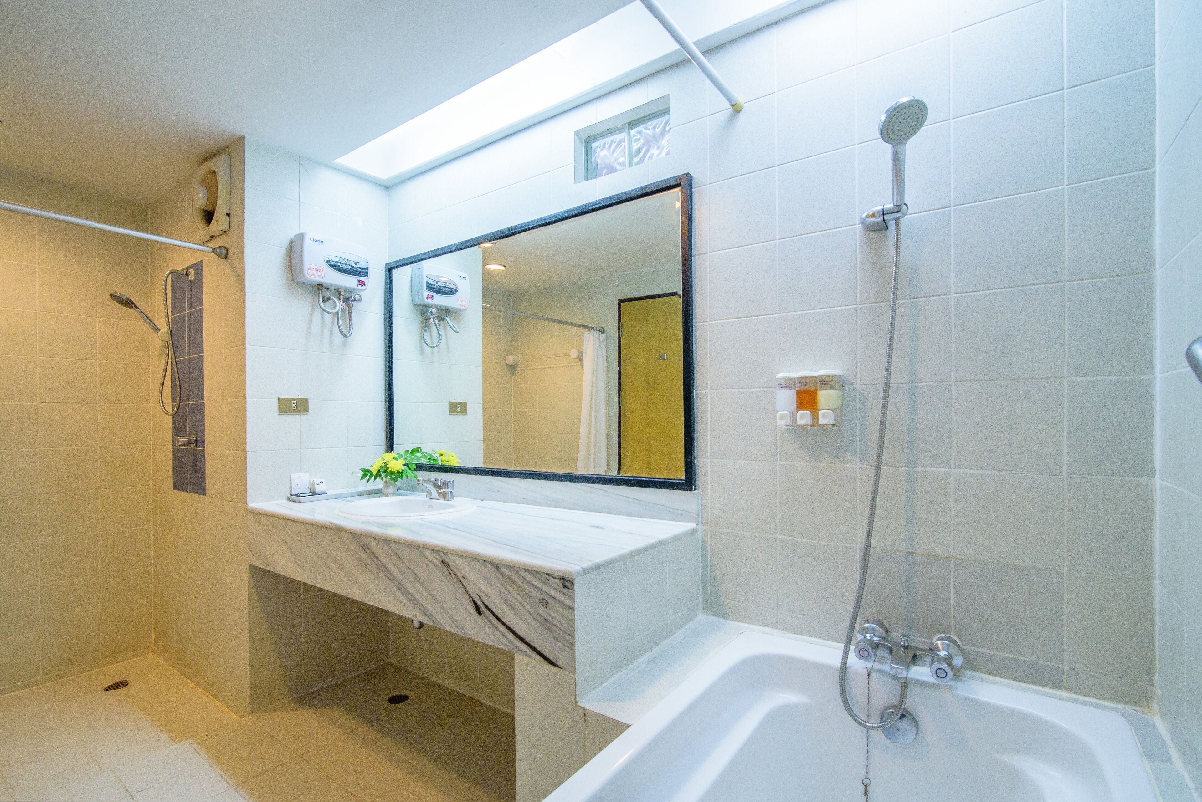 Une salle de bain moderne avec un lavabo en marbre, un grand miroir, une douche et une baignoire.