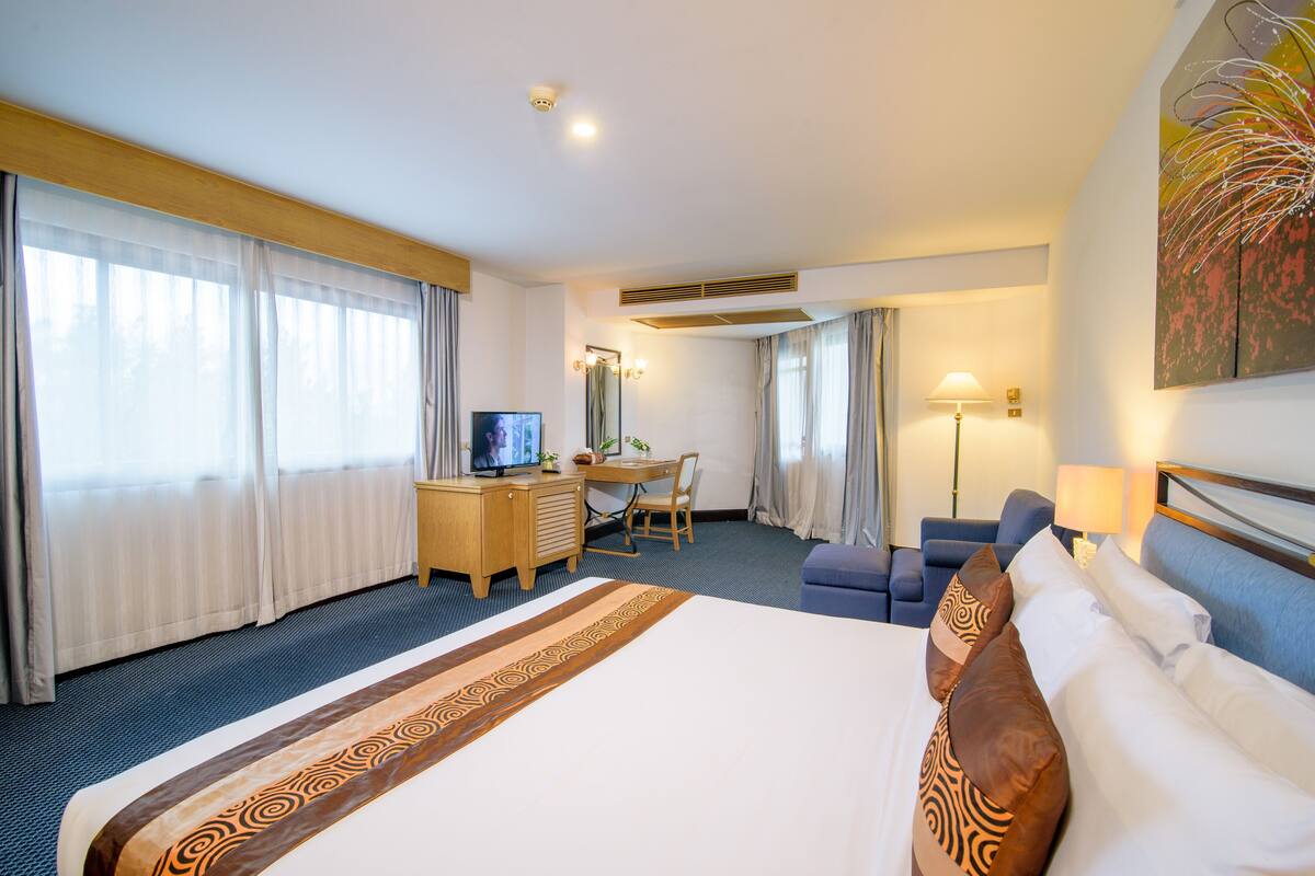Hotelkamer met een groot bed, een bureau met stoel, een televisie en een bank.