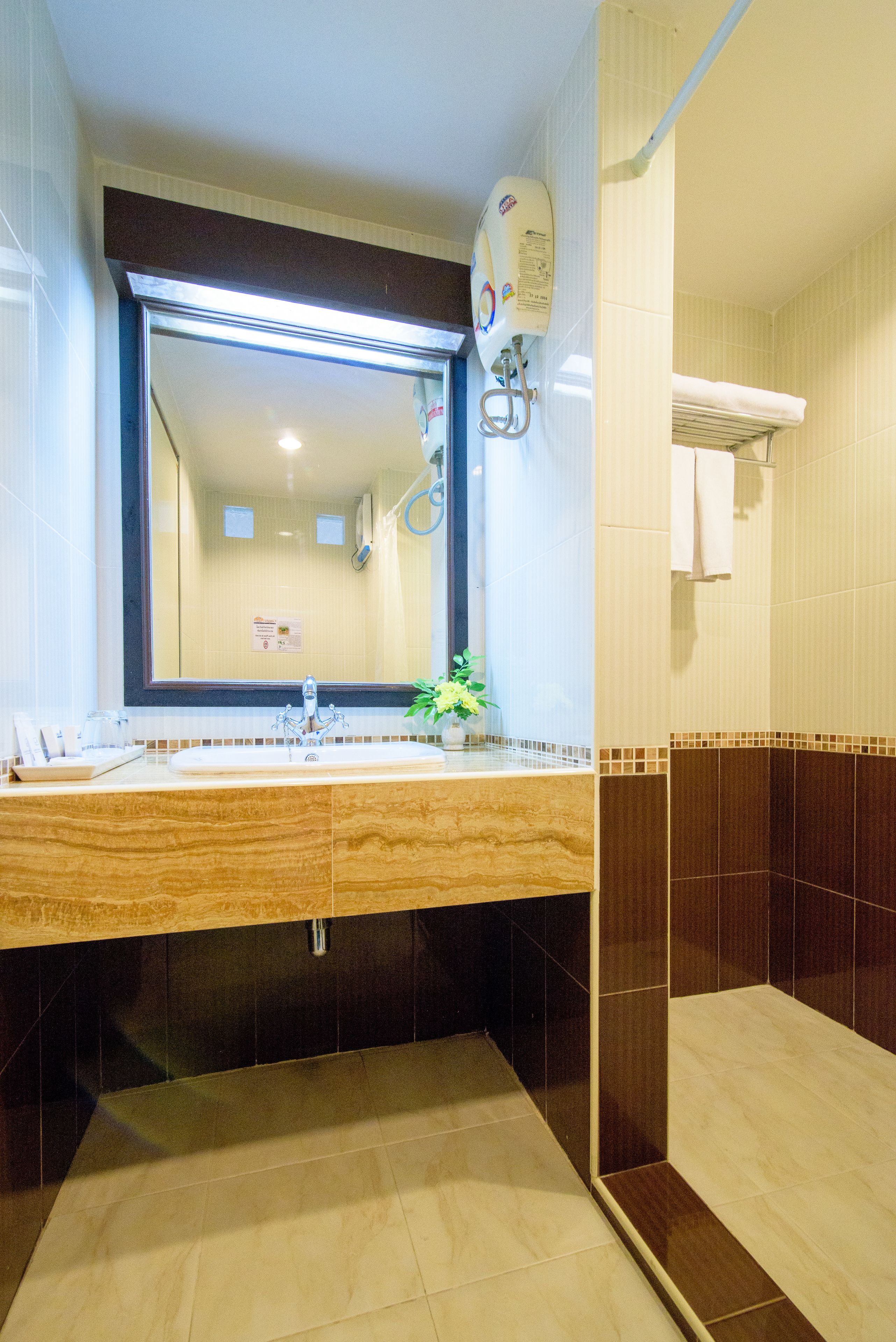 A bathroom with a large mirror, a sink with a marble countertop, a towel rack, and a shower area.