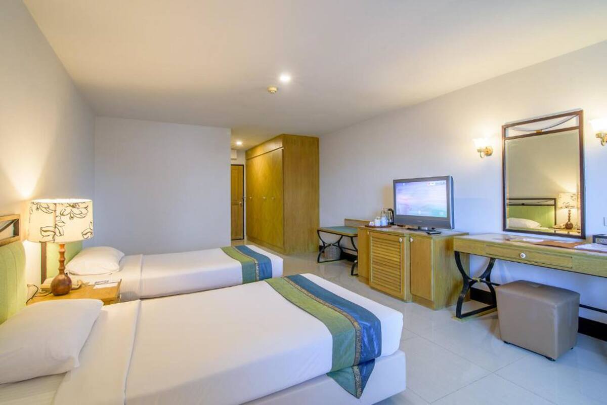 Een hotelkamer met twee bedden, een bureau, een televisie en een spiegel.