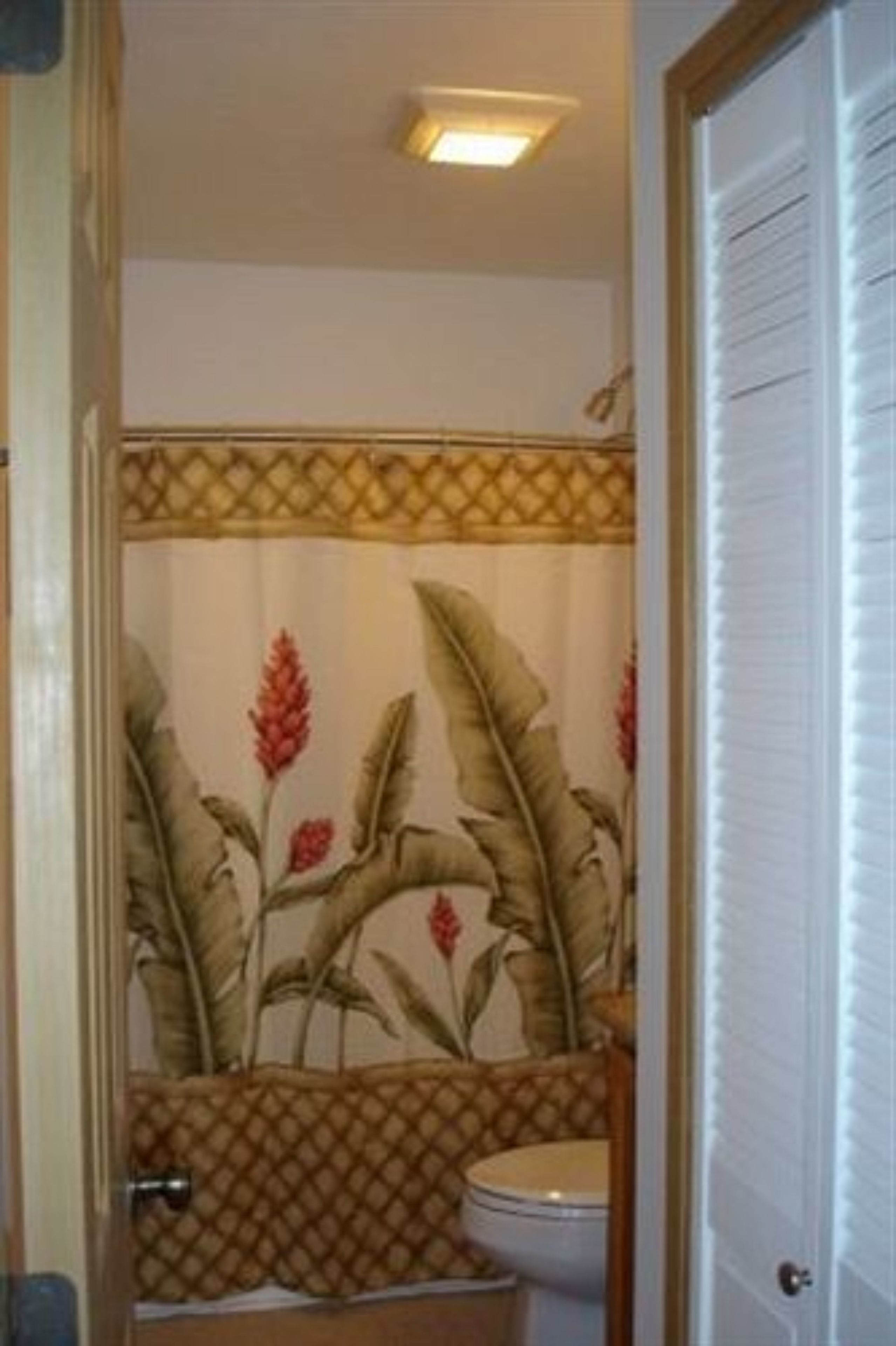 Un baño con inodoro, zona de ducha y un muro decorativo con motivos florales.