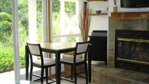 A modern kitchen with a dining table and chairs, a fireplace, and a television. - Bamboo Valley Inn (Haiku)