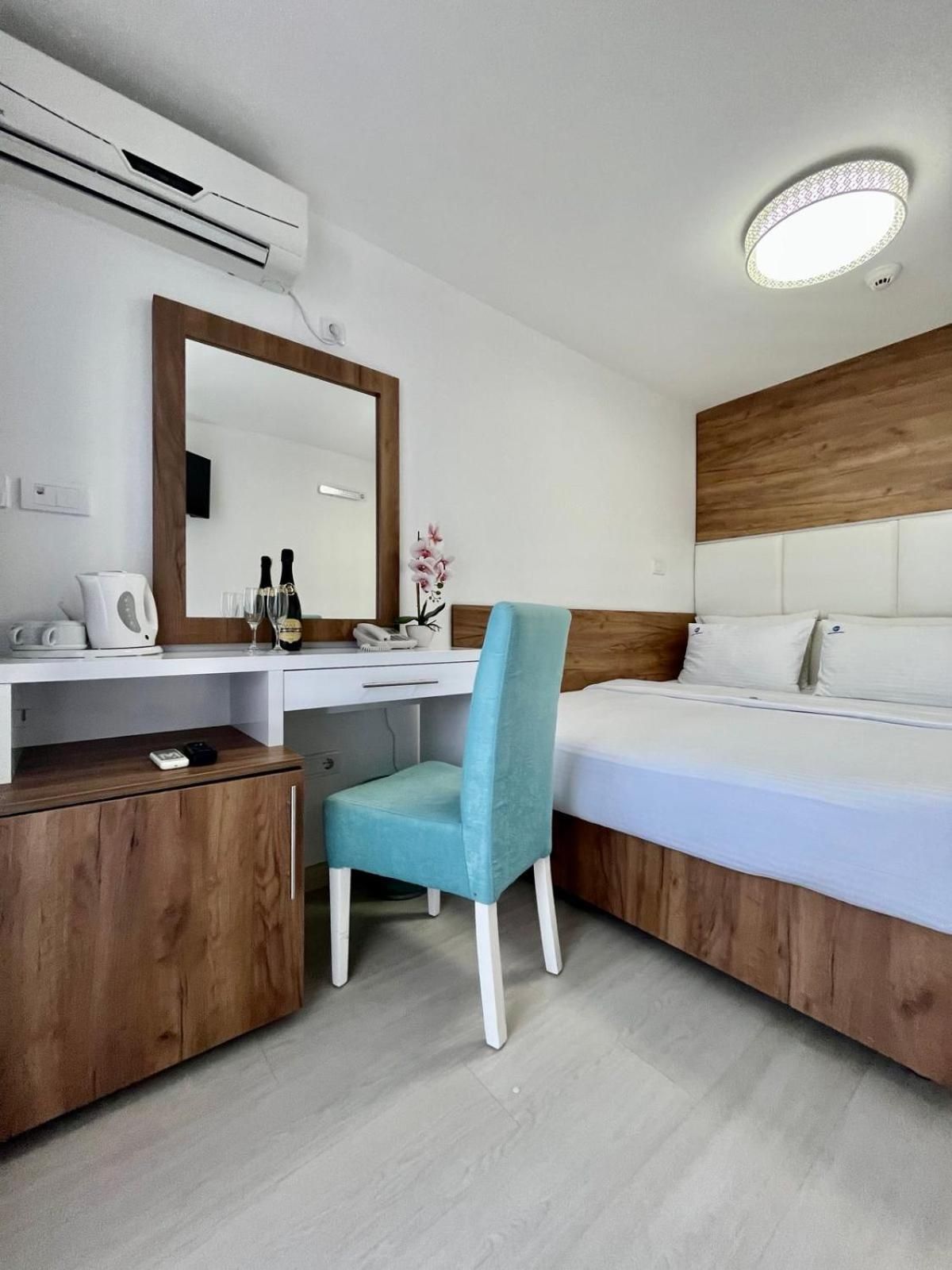A hotel room with a desk, chair, bed, and a large mirror.