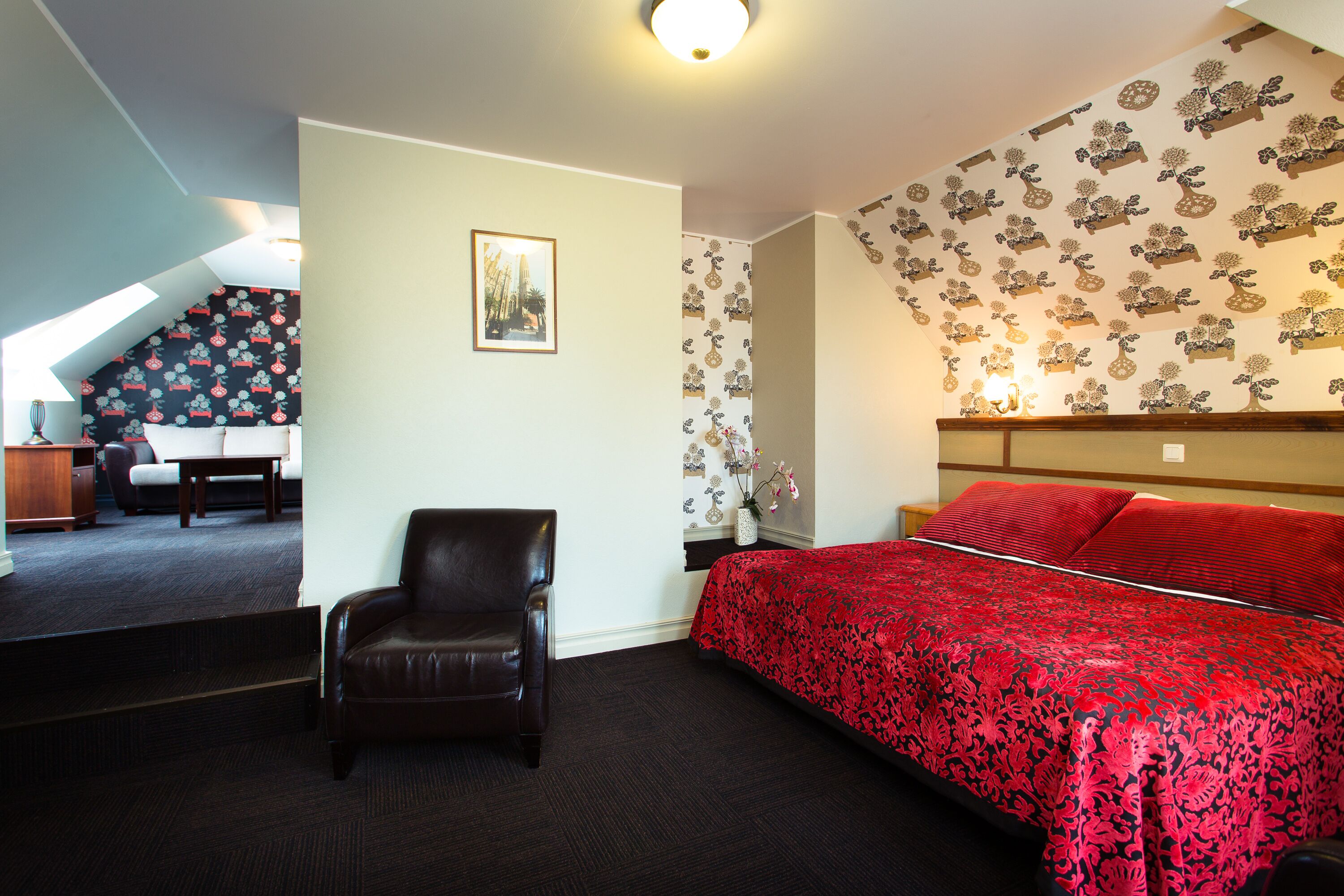 A bedroom with a bed, a chair, a desk, and a staircase.