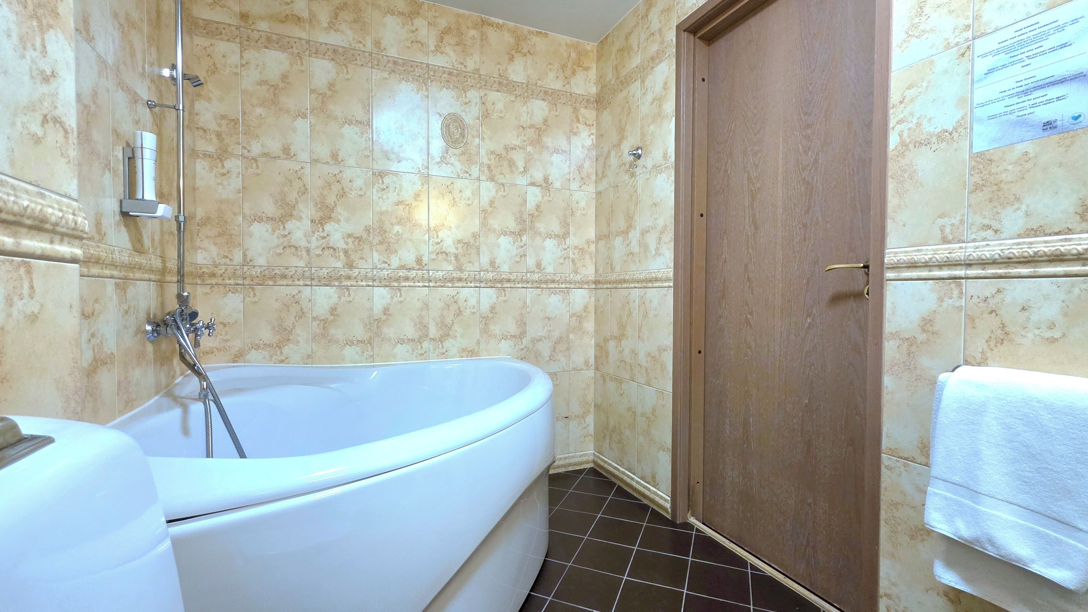 A bathroom with a freestanding bathtub, a showerhead, and a wooden door.