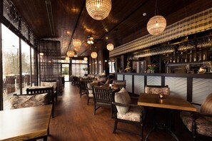 Un restaurante con suelos de madera, sillas estampadas y candelabros colgantes.
