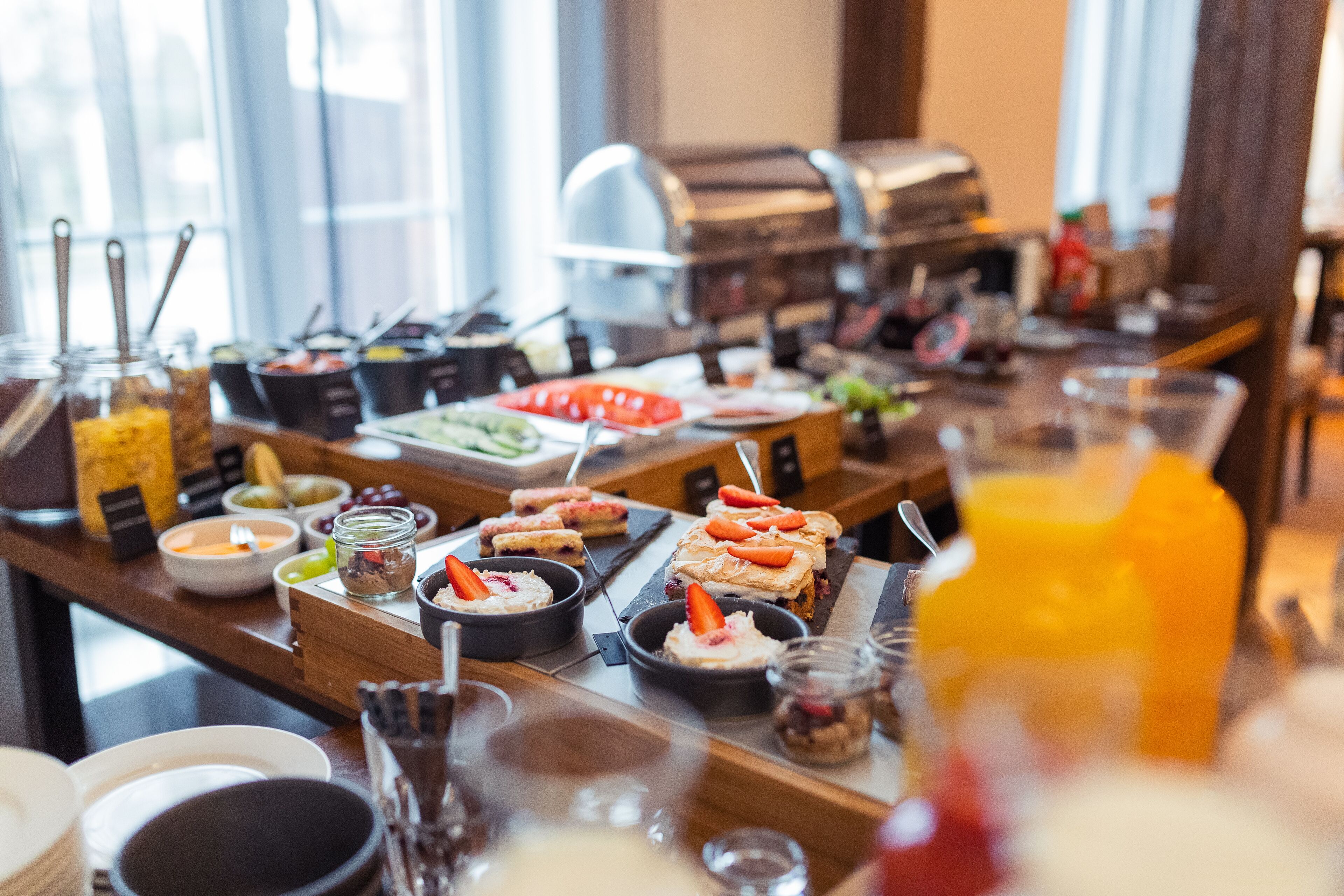 Un buffet con diversi cibi e un distributore di succo di frutta.