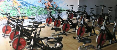 A gym with multiple stationary bikes and a mural of a cyclist on the wall.