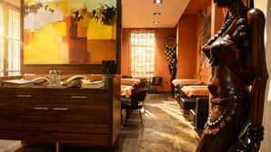 A restaurant with a wooden counter, a statue, and a large painting on the wall. - Afrika Hotel (Frydek-Mistek)