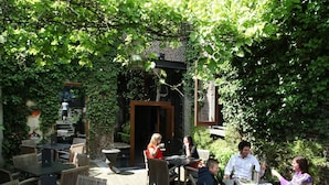 An outdoor patio with brick flooring, wooden furniture, and lush greenery. - Hotel De Groene Hendrickx (Hasselt)