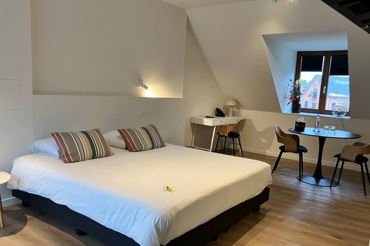 A bedroom with a large bed, a desk, and a small table.