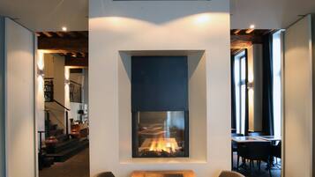 A modern living room with a fireplace, wooden dining table, and comfortable seating.