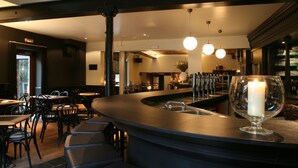 A modern bar area with stools, a counter, and a glass with a candle. - Hotel De Groene Hendrickx (Hasselt)