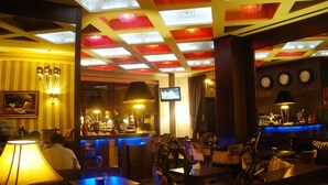 A bar area with tables, chairs, and a television screen. - Hotel Doro City (Tirana)
