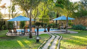 Un patio trasero con piscina, mobiliario exterior y un sendero de piedra.