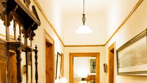 Un pasillo con piso de madera, un aparador de madera con espejo y una lámpara colgante.