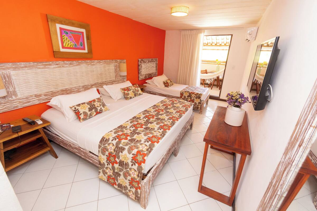 Habitación de hotel con dos camas, televisión, una mesita y ventana con cortinas.