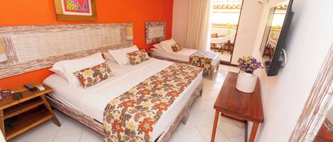 A hotel room with two beds, a TV, a small table, and a window with curtains.