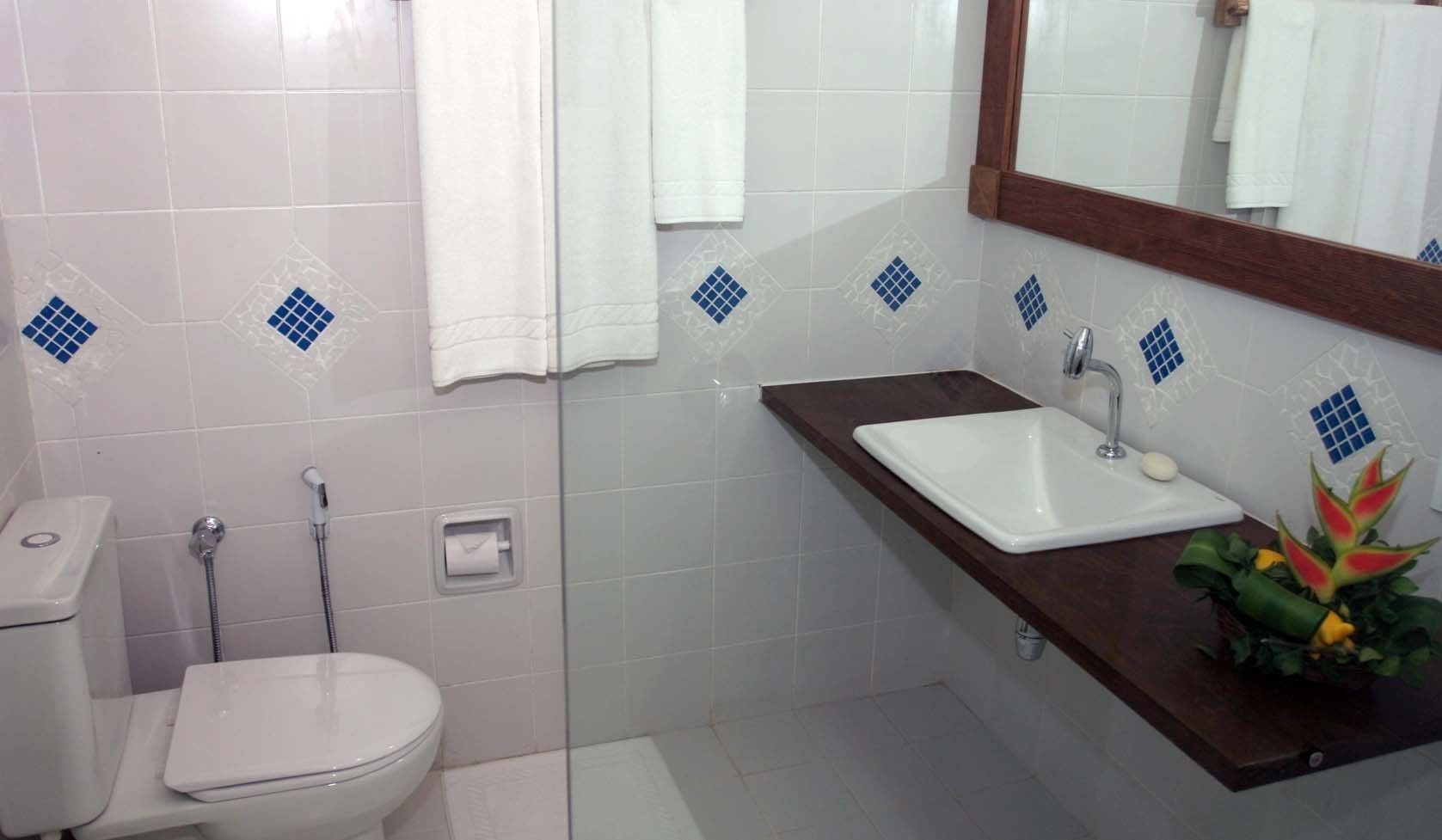 A bathroom with a toilet, a shower, a sink, and a mirror.