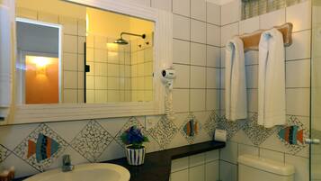A bathroom with a sink, mirror, shower, and toilet.