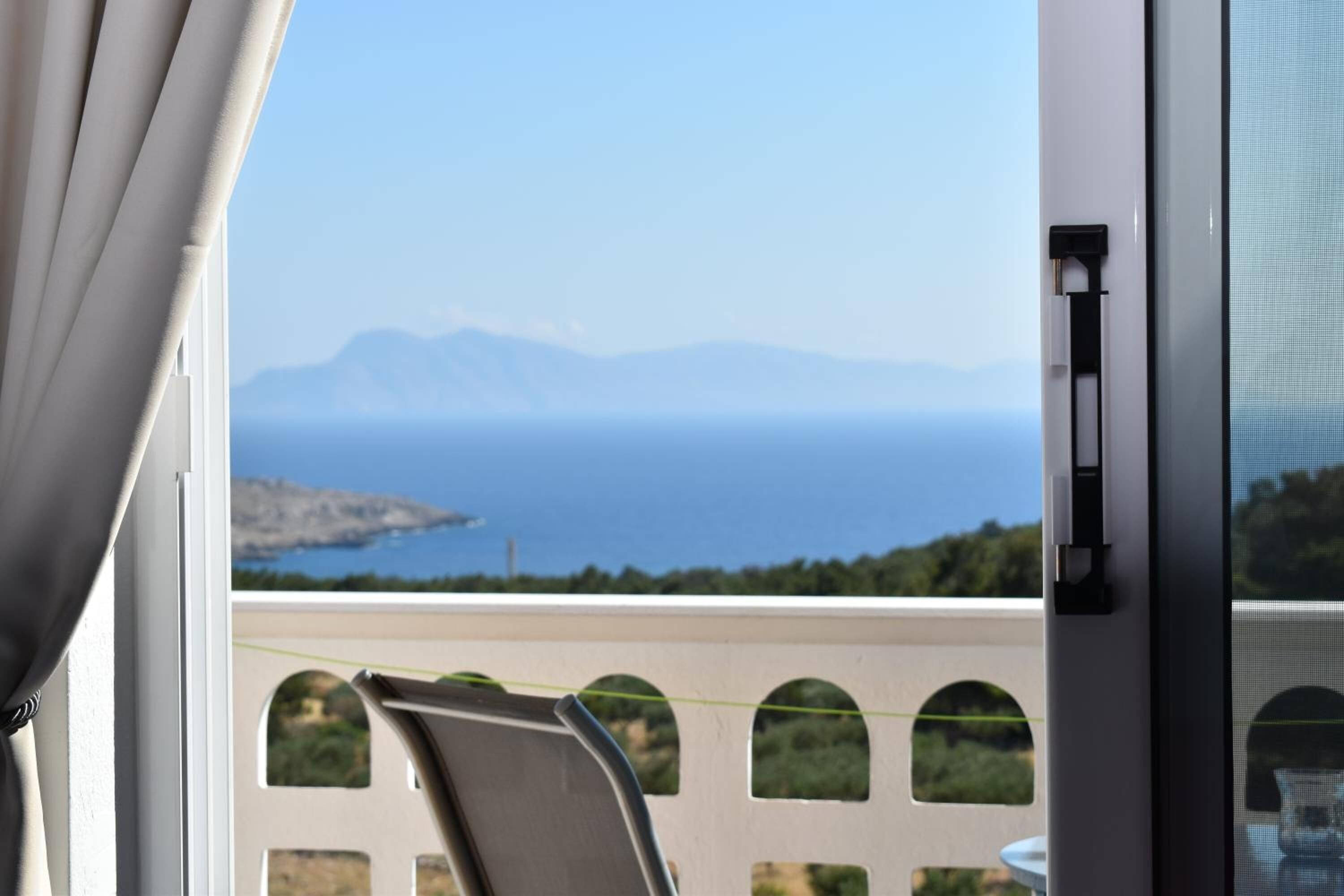 A balcony with a view of the sea and mountains.