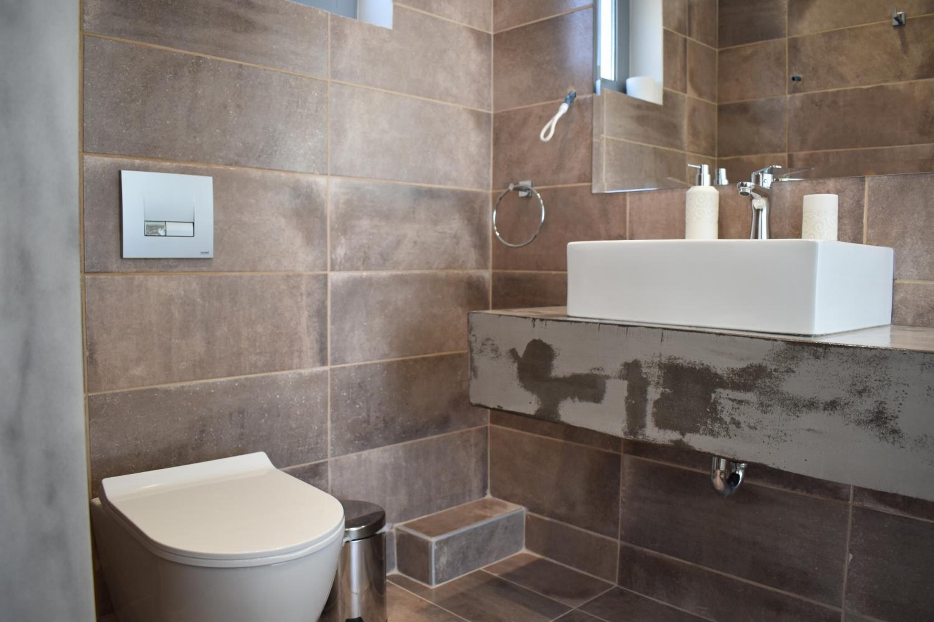 A modern bathroom with a white toilet, a rectangular sink, and a shower.