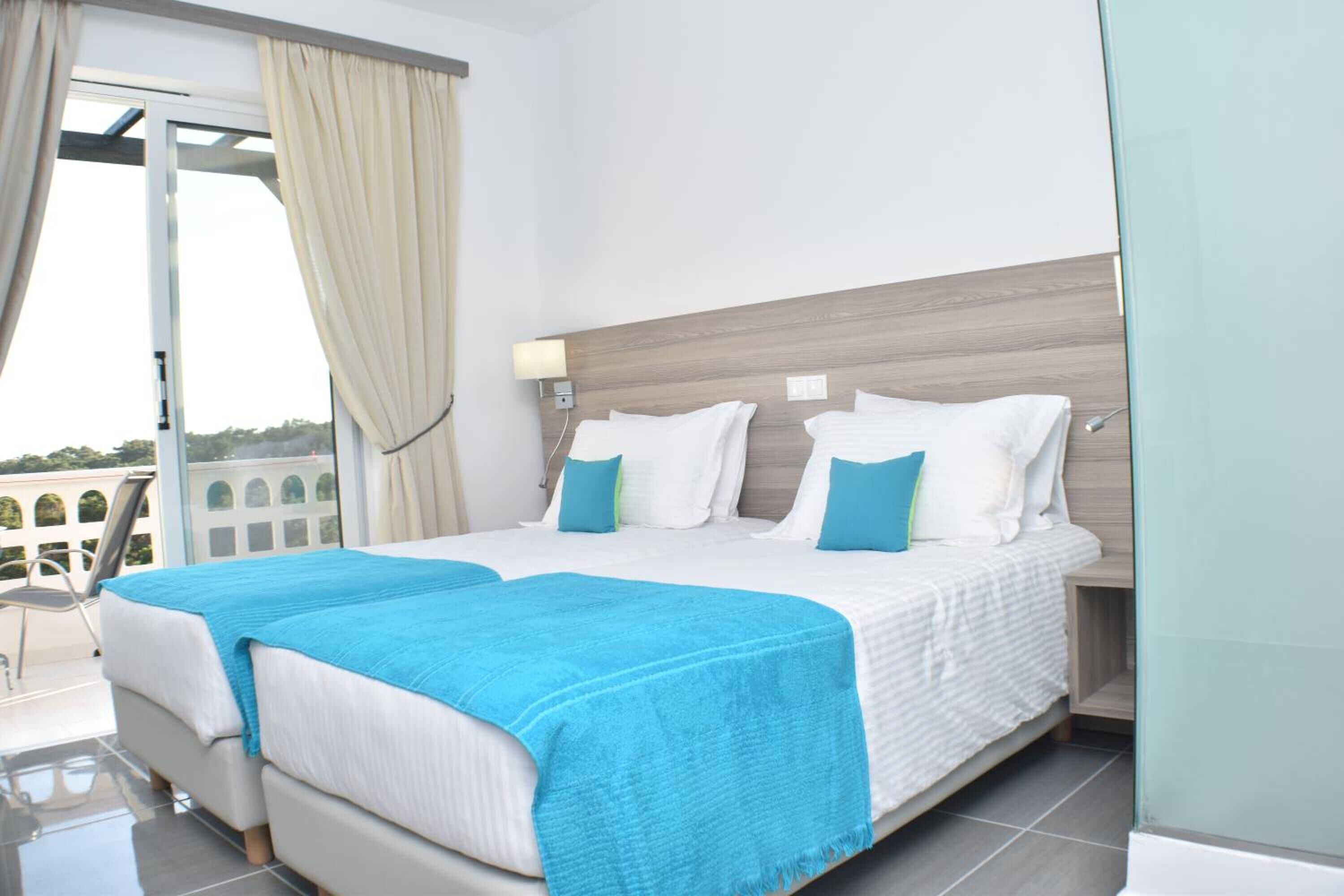Une chambre d’hôtel avec un grand lit, un balcon avec des rideaux et une vue sur l’extérieur.