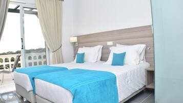 Une chambre d’hôtel avec un grand lit, un balcon avec des rideaux et une vue sur l’extérieur.