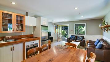 A modern kitchen with white cabinets, a stainless steel refrigerator, and a dining area with a wooden table and chairs.