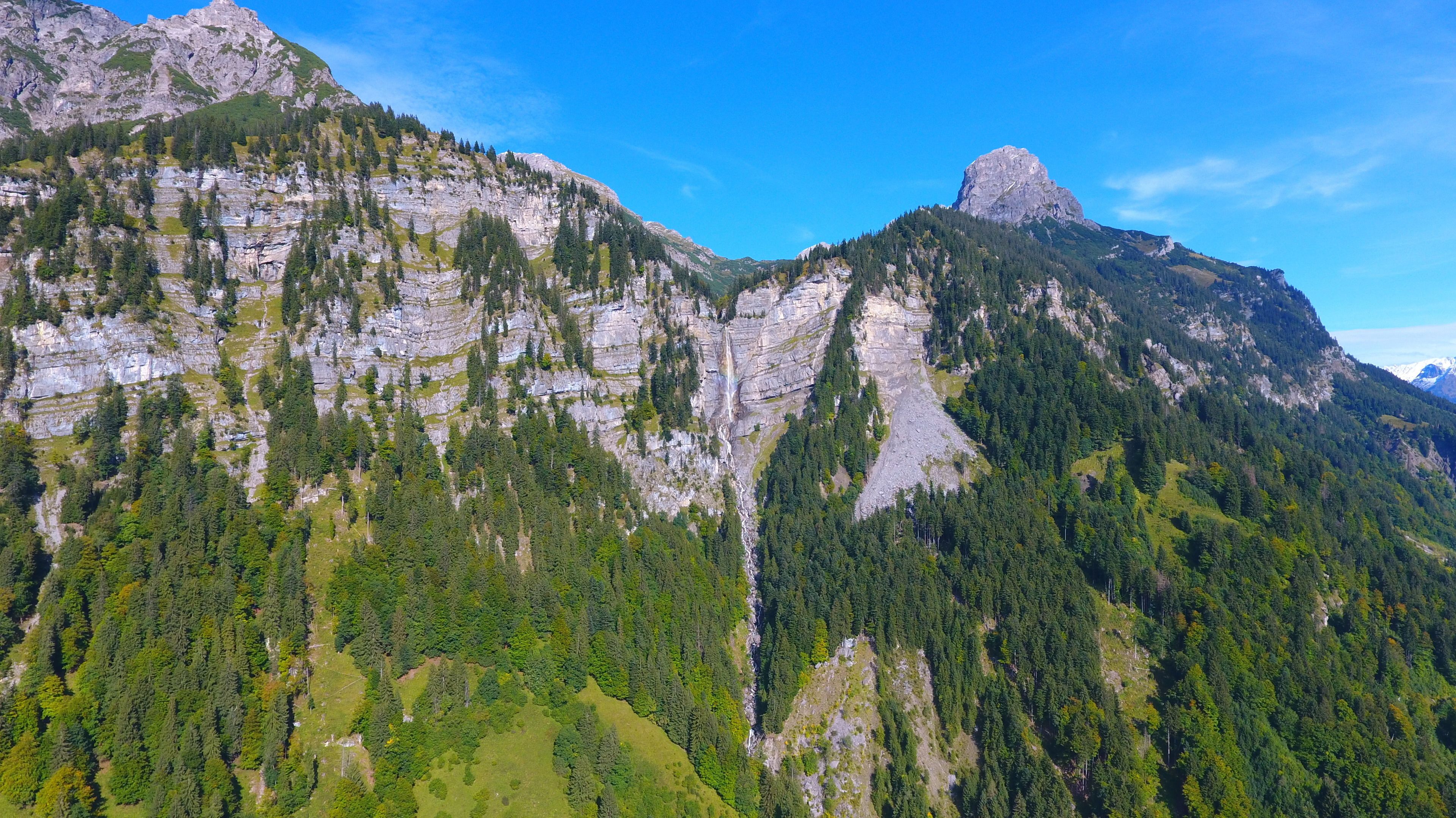 Un paisaje montañoso con densos bosques y acantilados rocosos.