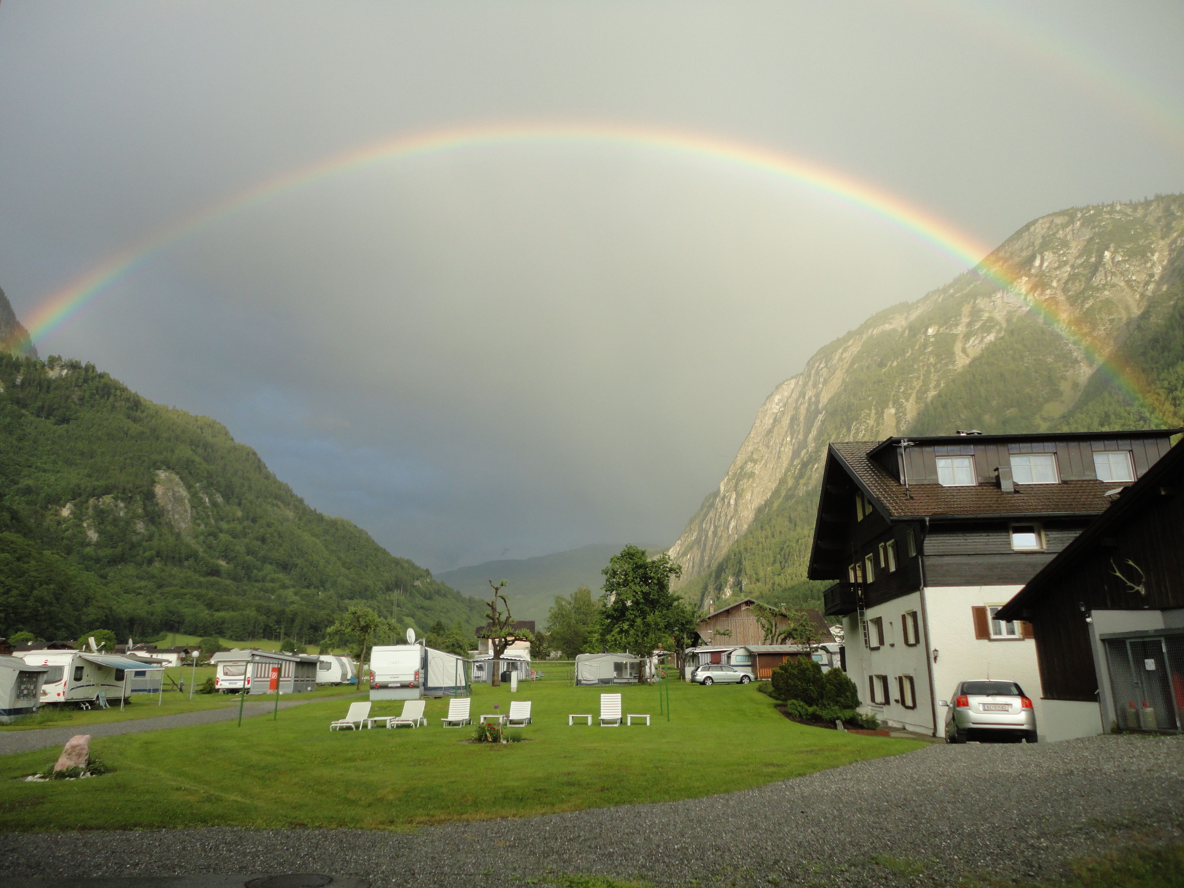 A campground with RVs, a building with a sloped roof, and a mountain backdrop.