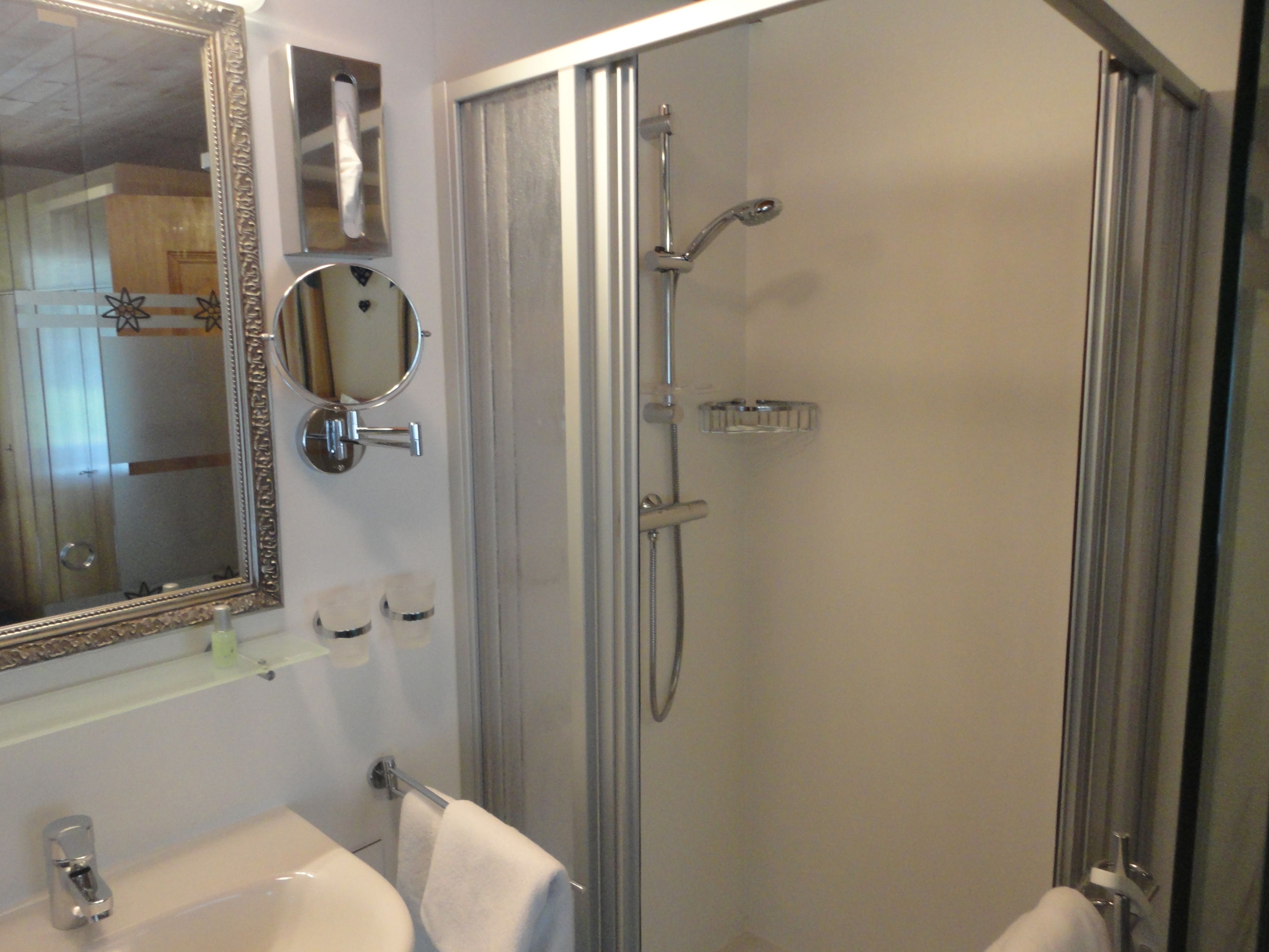 A bathroom with a sink, mirror, and shower.