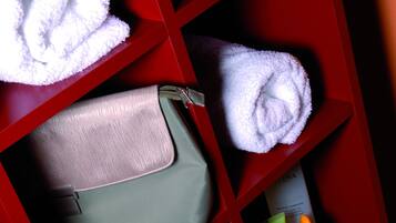 A red storage unit with towels, a handbag, and toiletries.